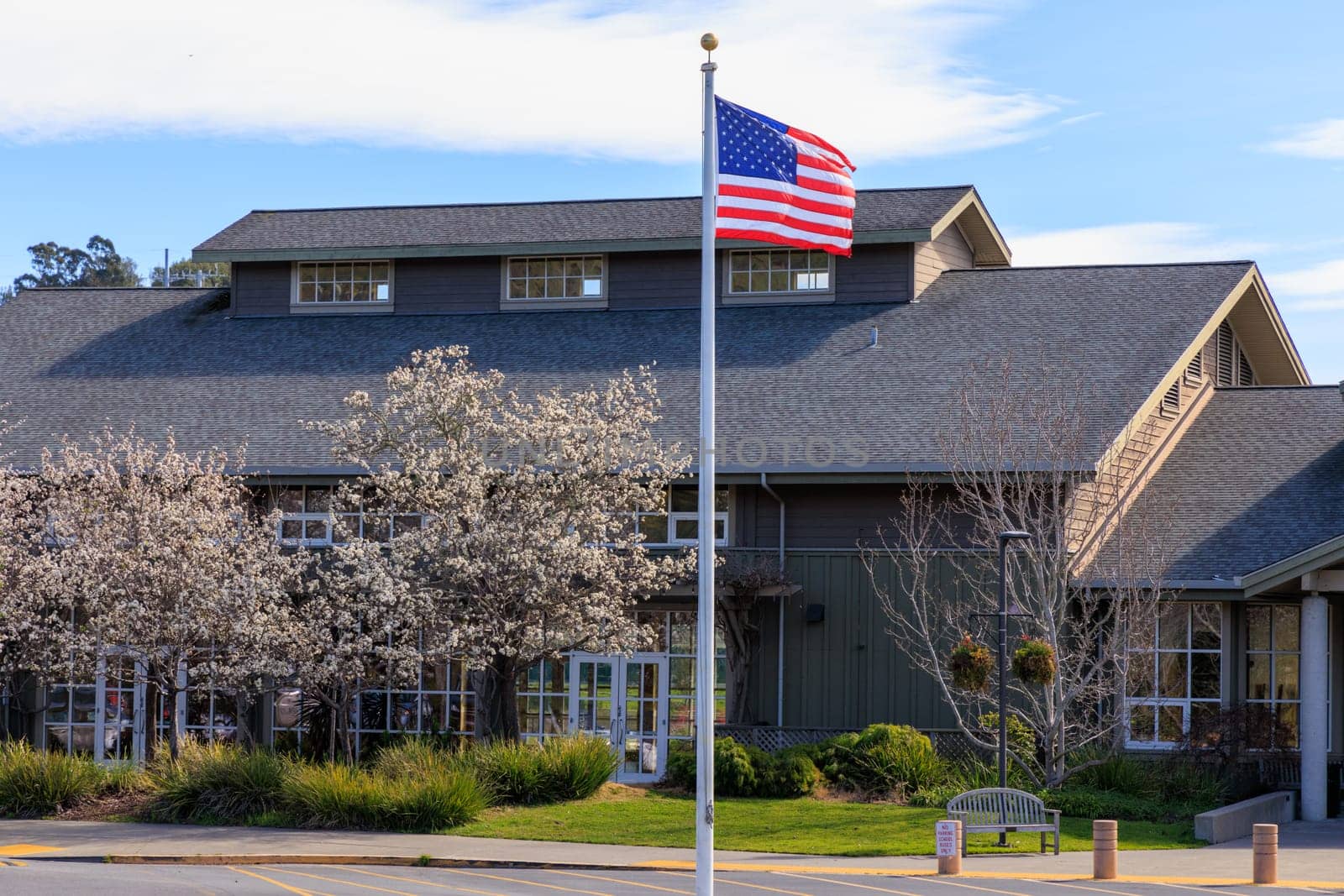 American flag flies over small town community center building on sunny day. High quality photo