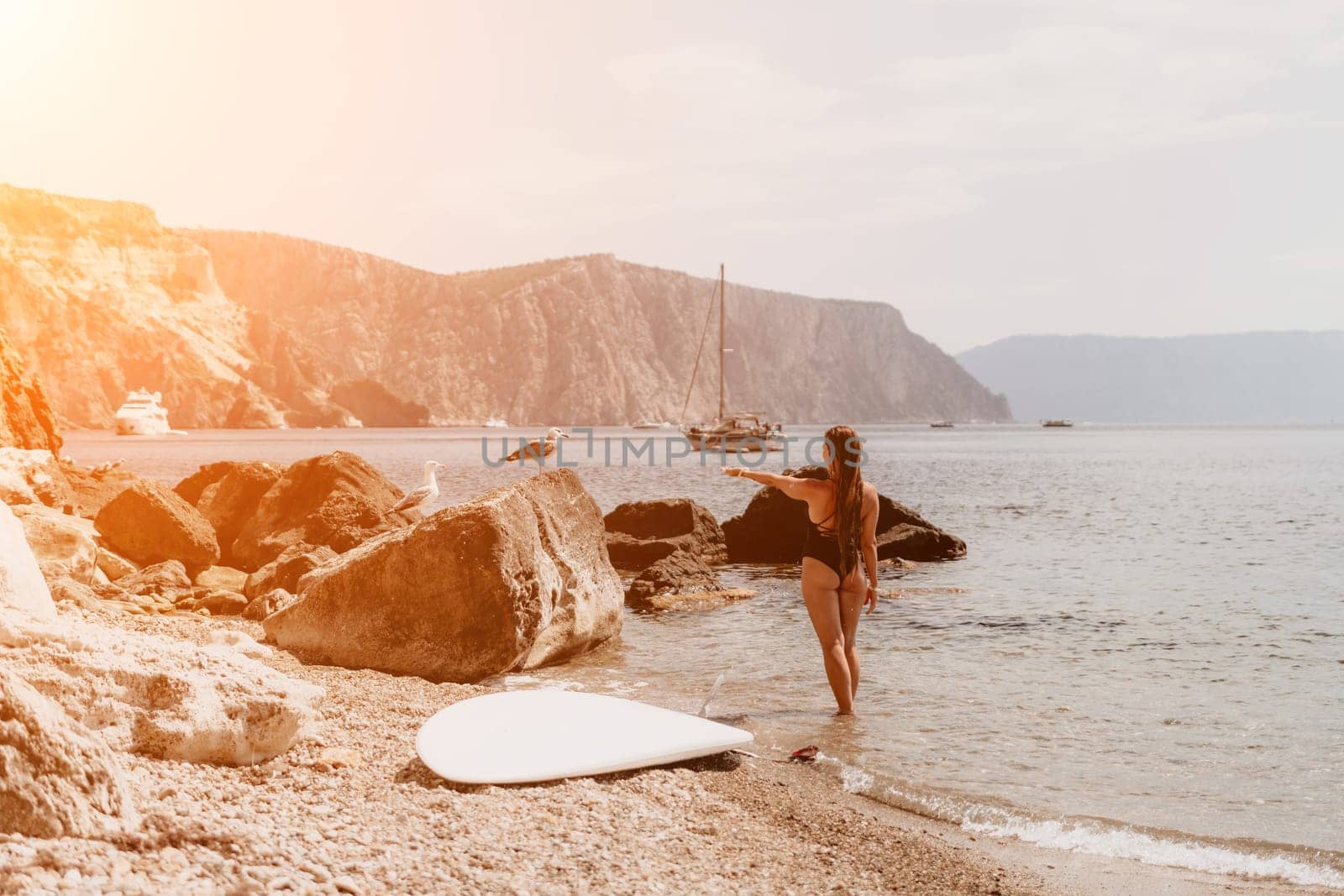 Woman travel sea. Young Happy woman in a long red dress posing on a beach near the sea on background of volcanic rocks, like in Iceland, sharing travel adventure journey