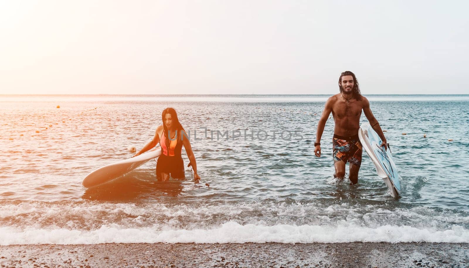 Sea woman and man on sup. Silhouette of happy young woman and man, surfing on SUP board, confident paddling through water surface. Idyllic sunset. Active lifestyle at sea or river. by panophotograph