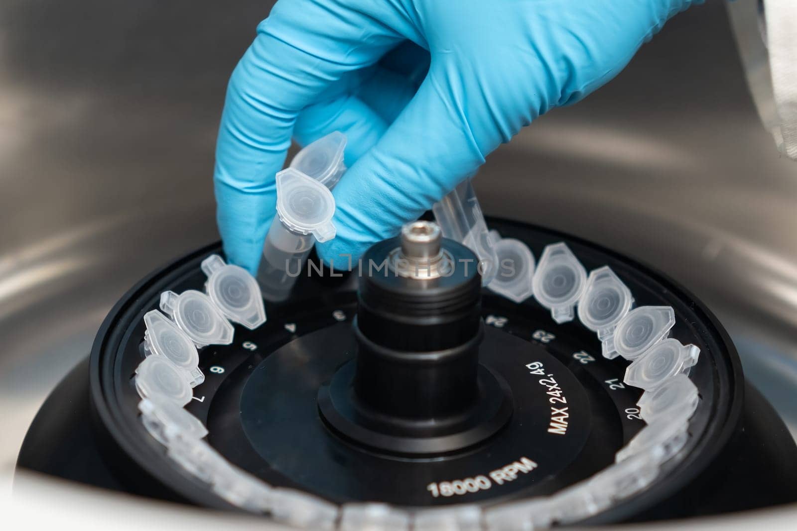 Scientist puts microcentrifuge tubes into centrifuge for phase separation. DNA and cell analysis at microbiology laboratory.