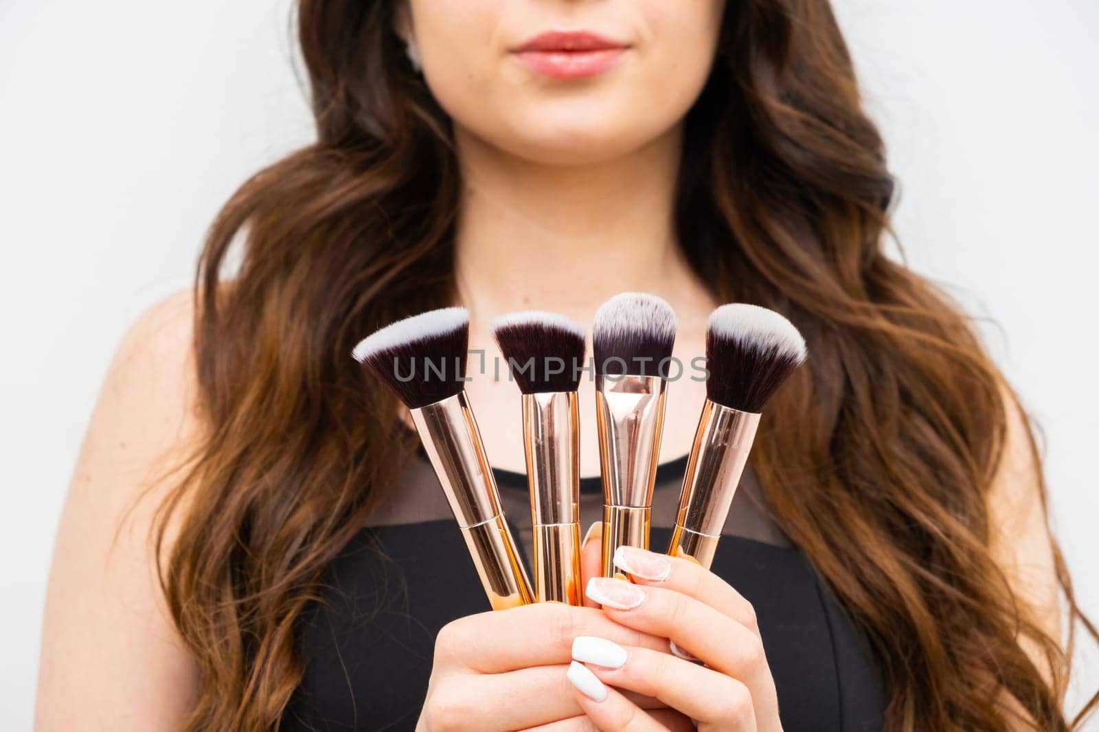 Woman holding makeup brushes in hands.