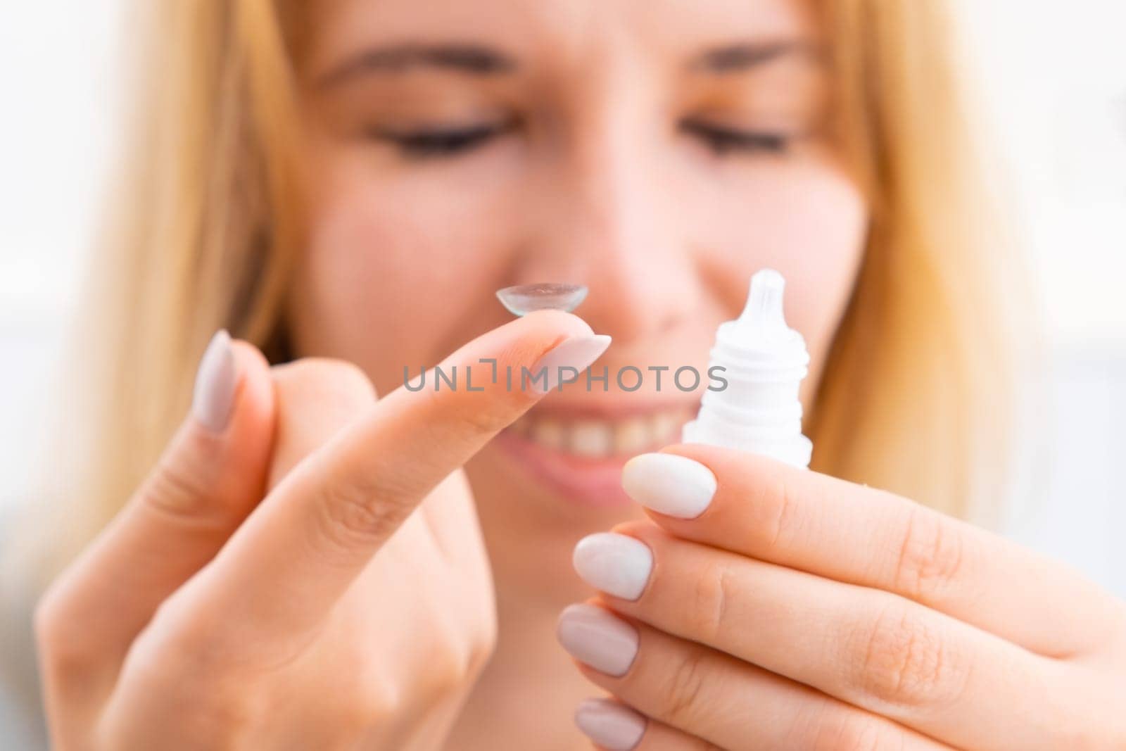 Woman with closed eyes holding eye lens and eye drops close to face