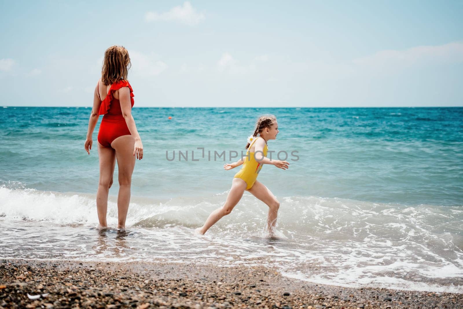 Happy loving family mother and daughter having fun together on the beach. Mum playing with her kid in holiday vacation next to the ocean - Family lifestyle and love concept.