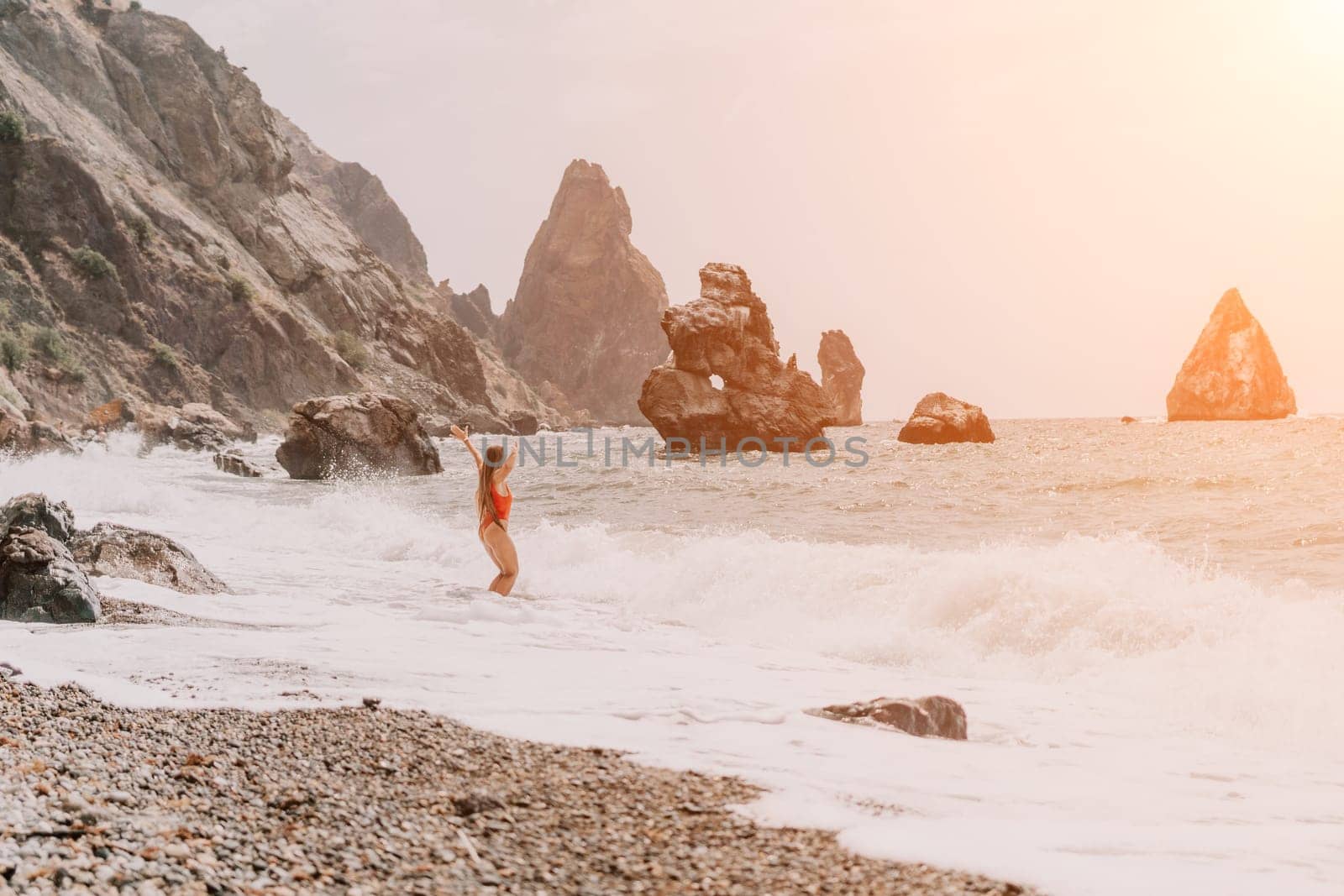 Woman summer travel sea. Happy tourist in red bikini enjoy taking picture outdoors for memories. Woman traveler posing on beach at sea surrounded by volcanic mountains, sharing travel adventure joy by panophotograph