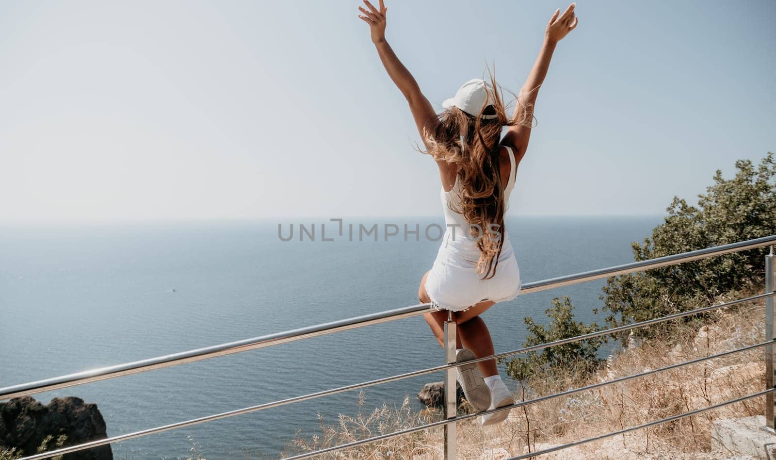 Woman travel sea. Young Happy woman in a long red dress posing on a beach near the sea on background of volcanic rocks, like in Iceland, sharing travel adventure journey