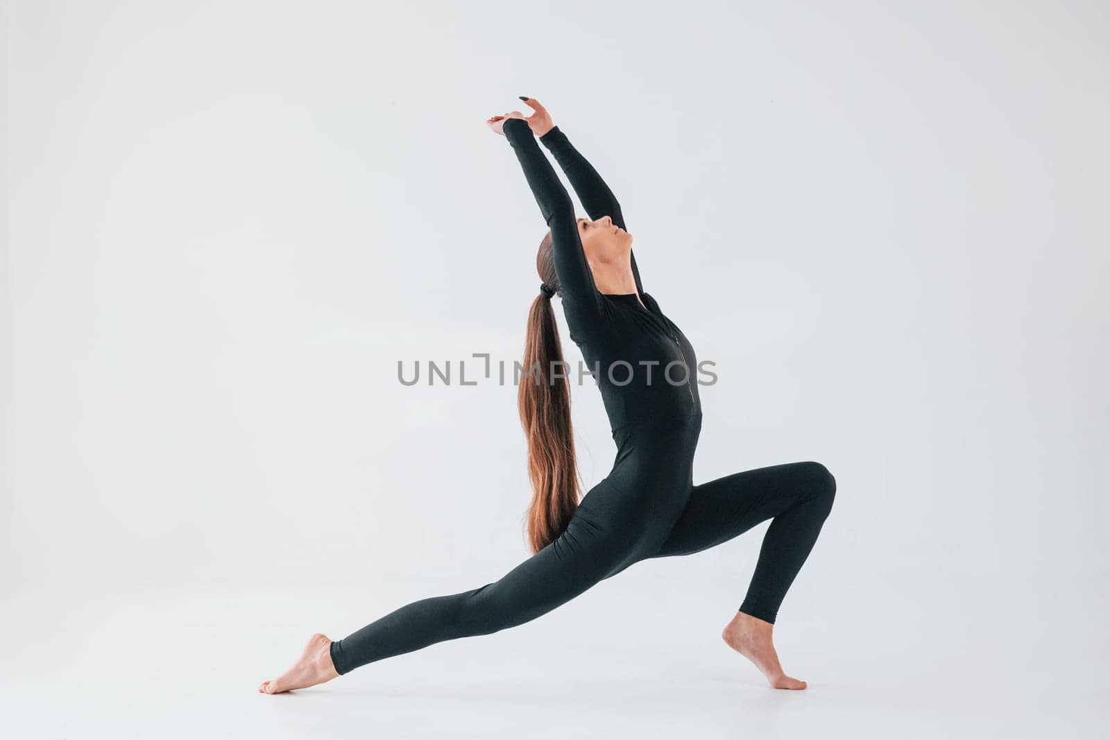Professional exercises. Young woman in sportive clothes doing gymnastics indoors.