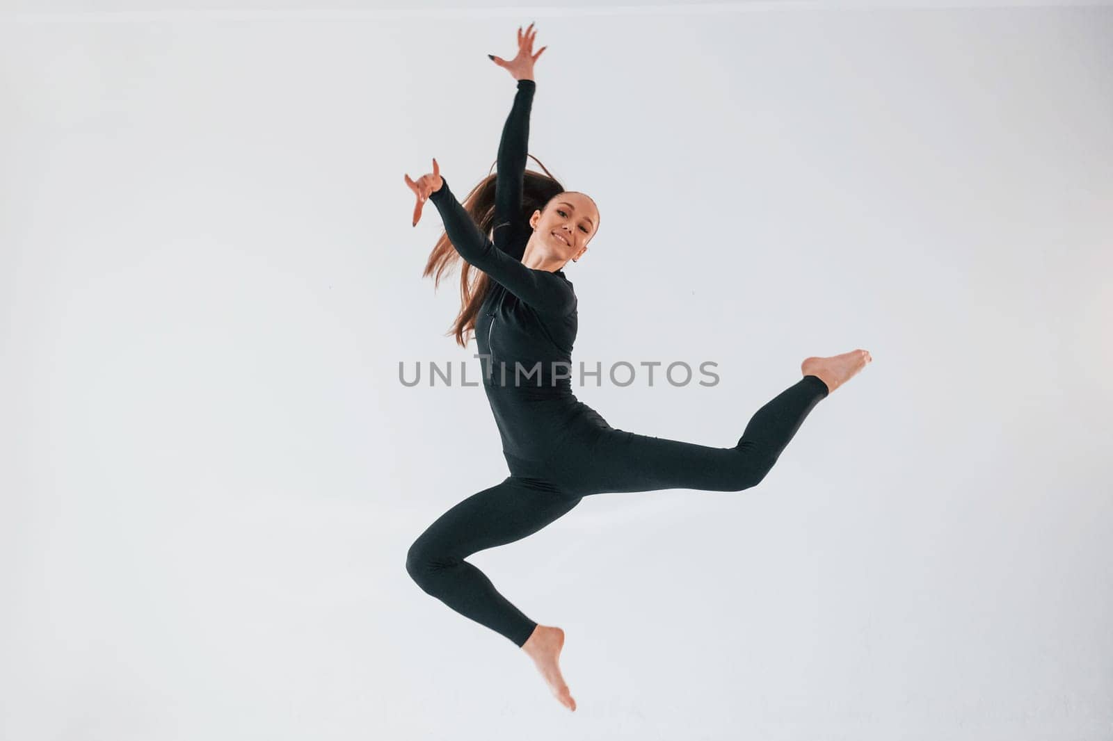 Professional exercises. Young woman in sportive clothes doing gymnastics indoors.