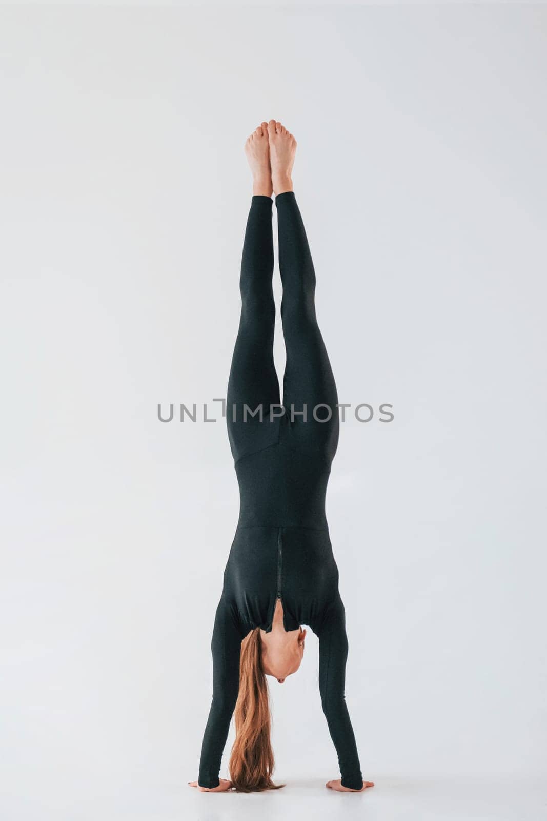 Practice routine. Young woman in sportive clothes doing gymnastics indoors.