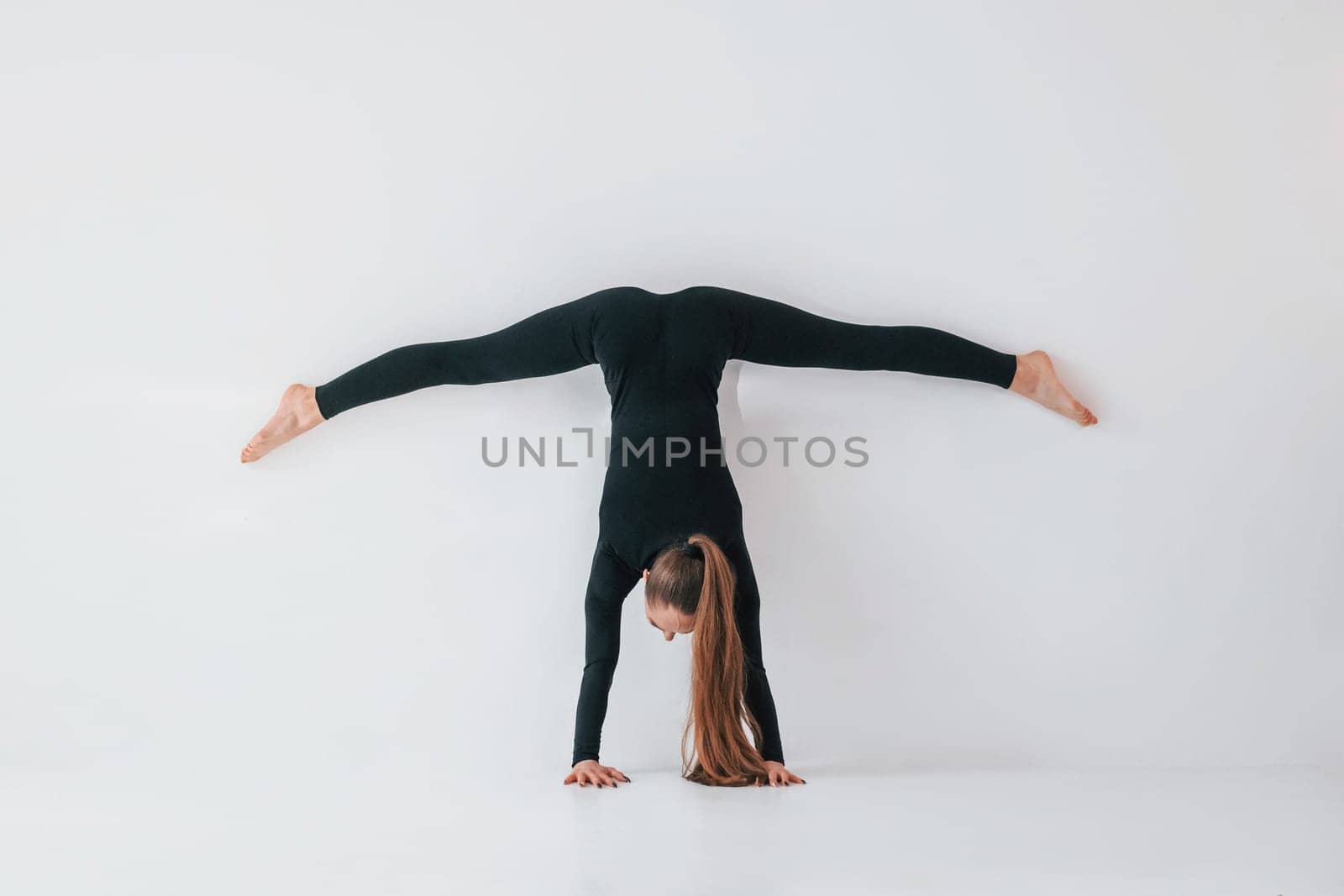 Practice routine. Young woman in sportive clothes doing gymnastics indoors.