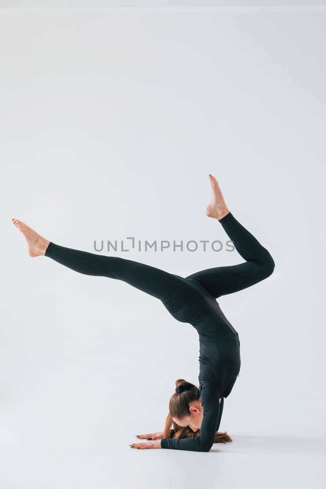 Practice routine. Young woman in sportive clothes doing gymnastics indoors.