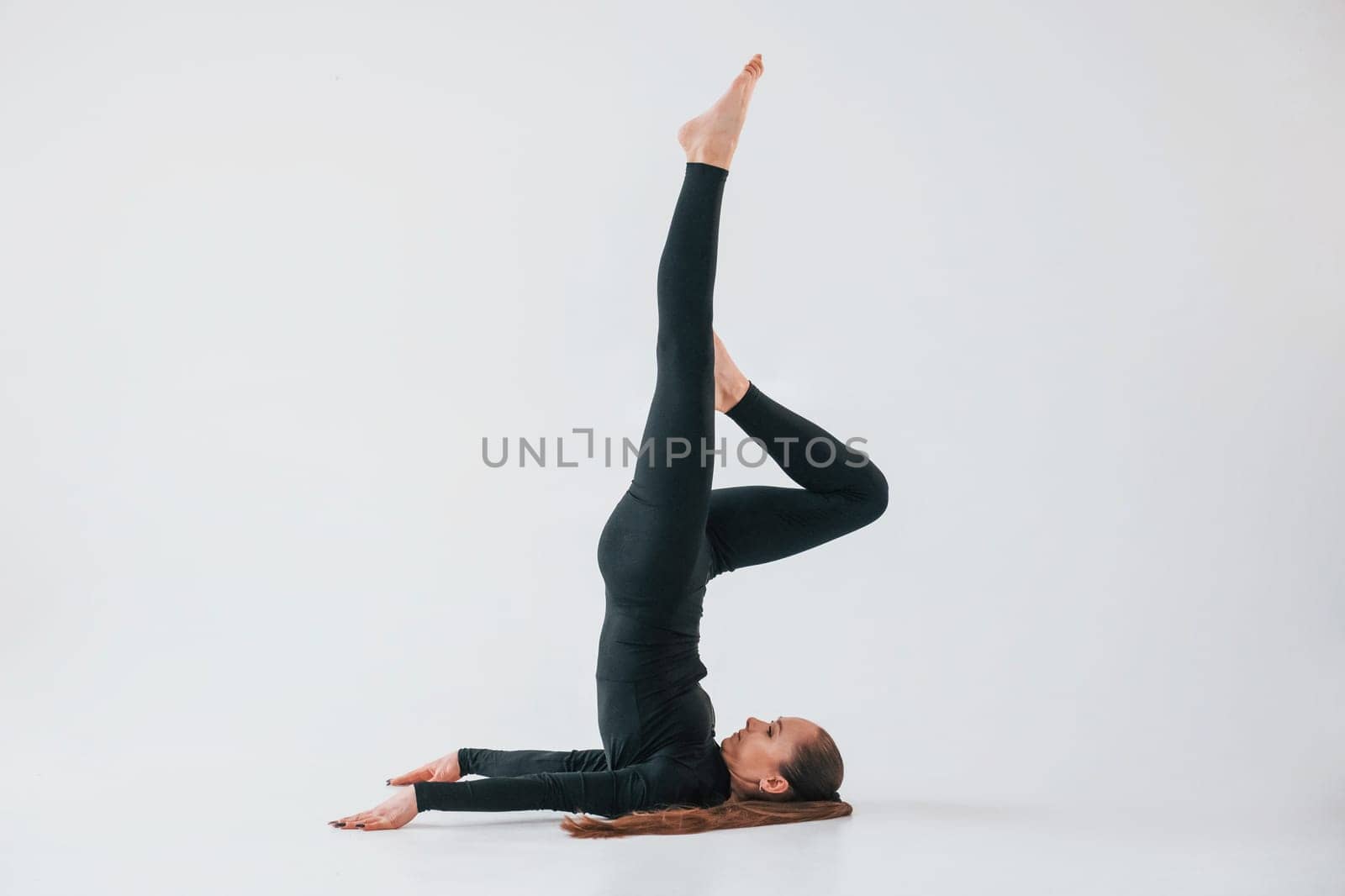 Practice routine. Young woman in sportive clothes doing gymnastics indoors.