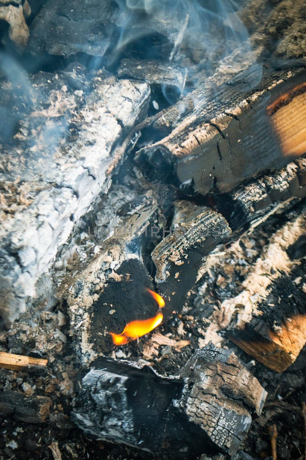 A fire burns in a campfire with a red fire in the background. High quality photo