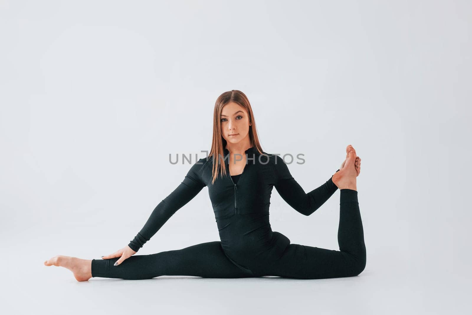 Side stretch. Young woman in sportive clothes doing gymnastics indoors.
