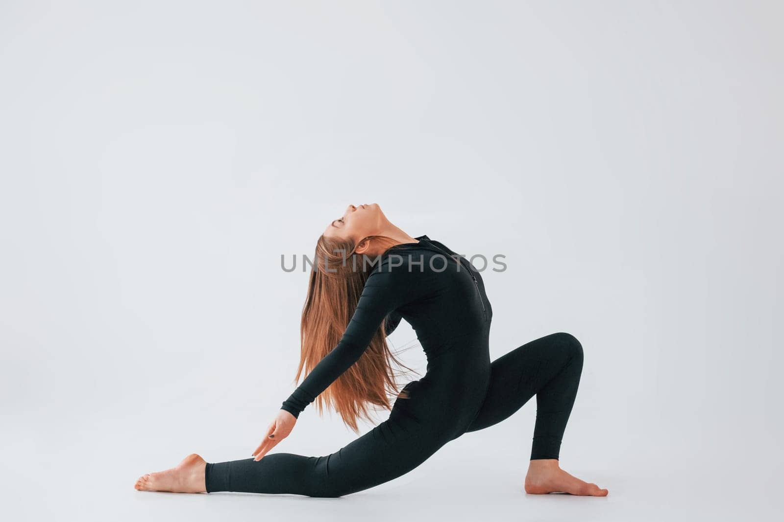 Side stretch. Young woman in sportive clothes doing gymnastics indoors.