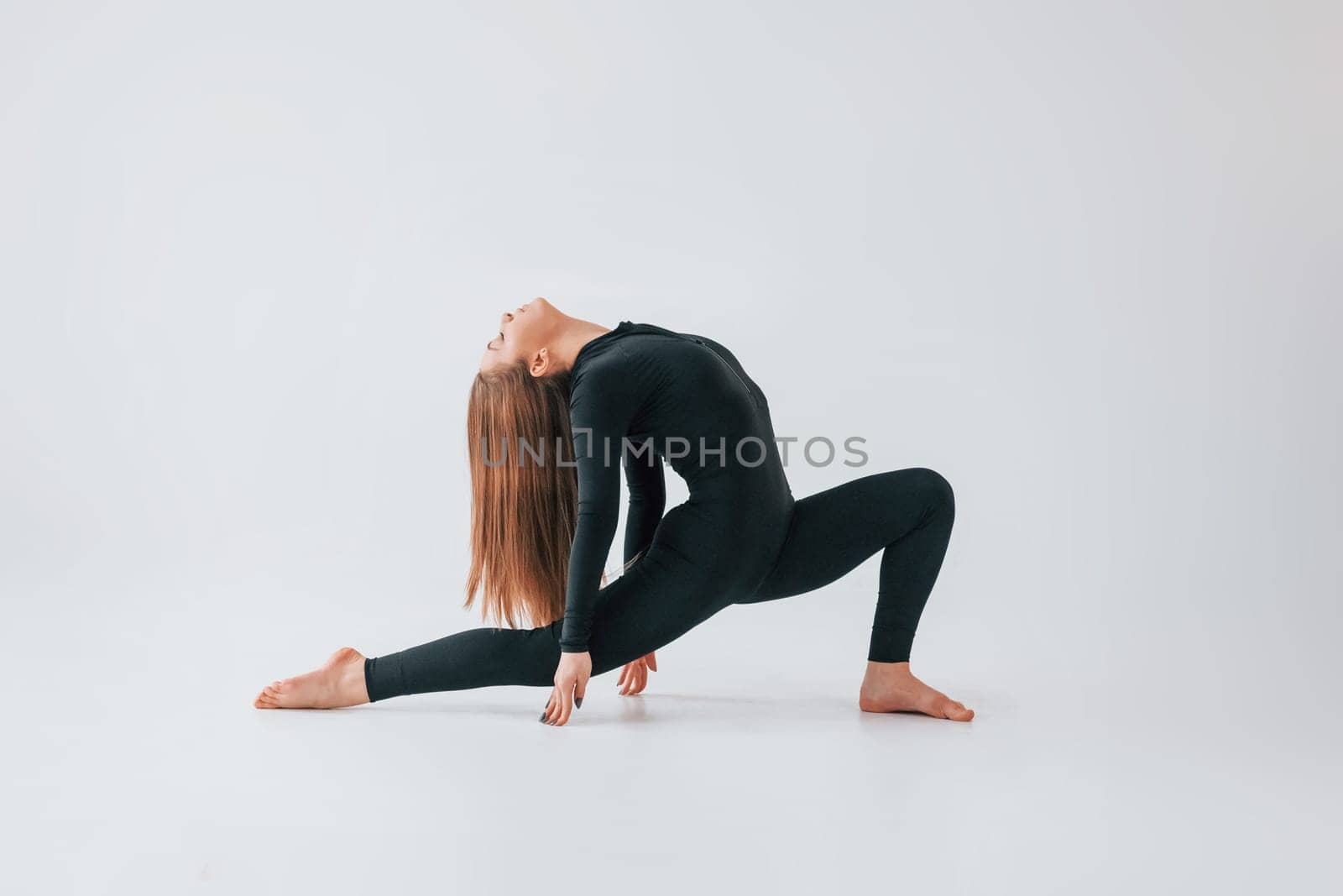 On the floor. Young woman in sportive clothes doing gymnastics indoors.
