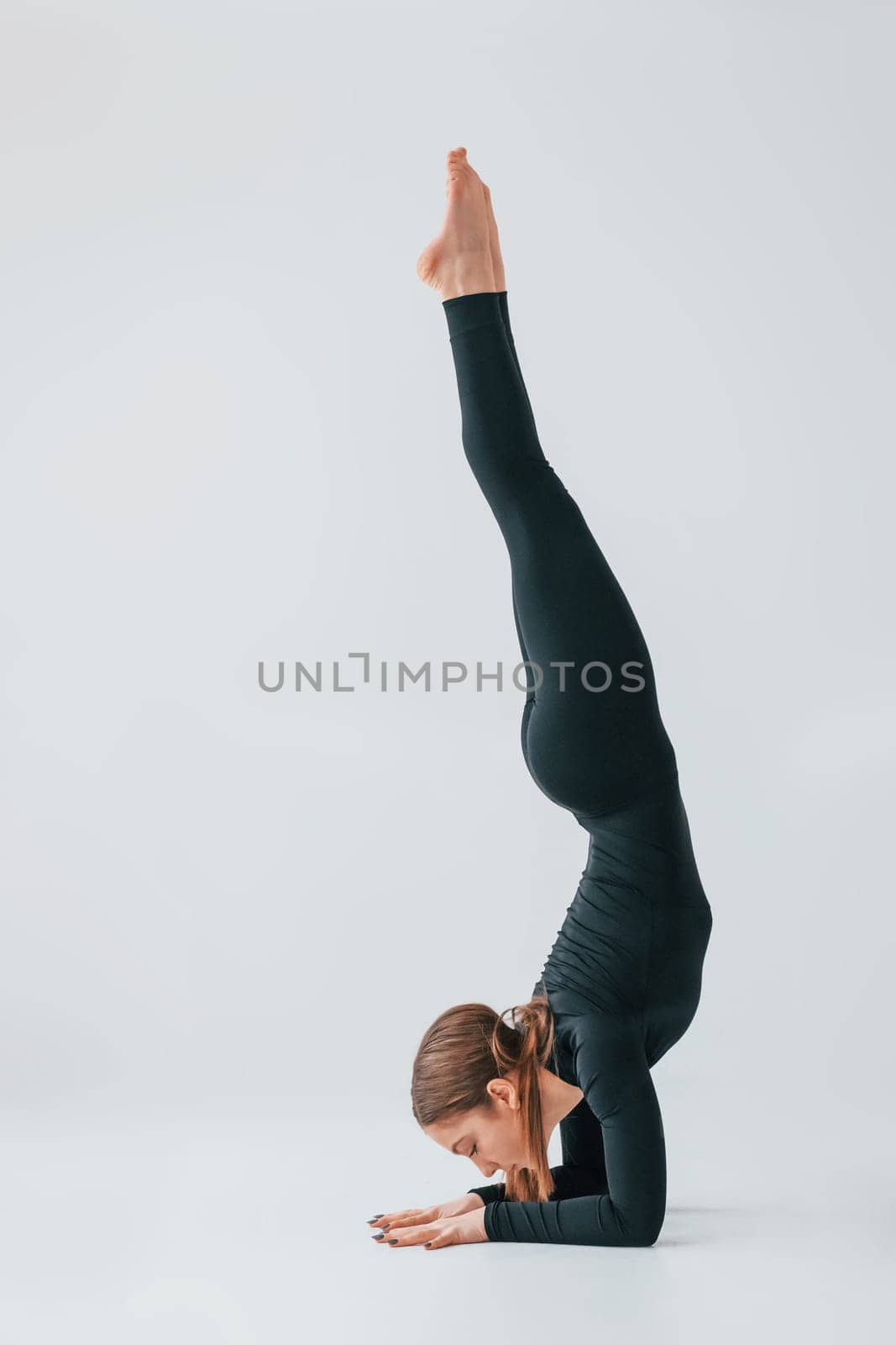 Difficult exercises. Young woman in sportive clothes doing gymnastics indoors.