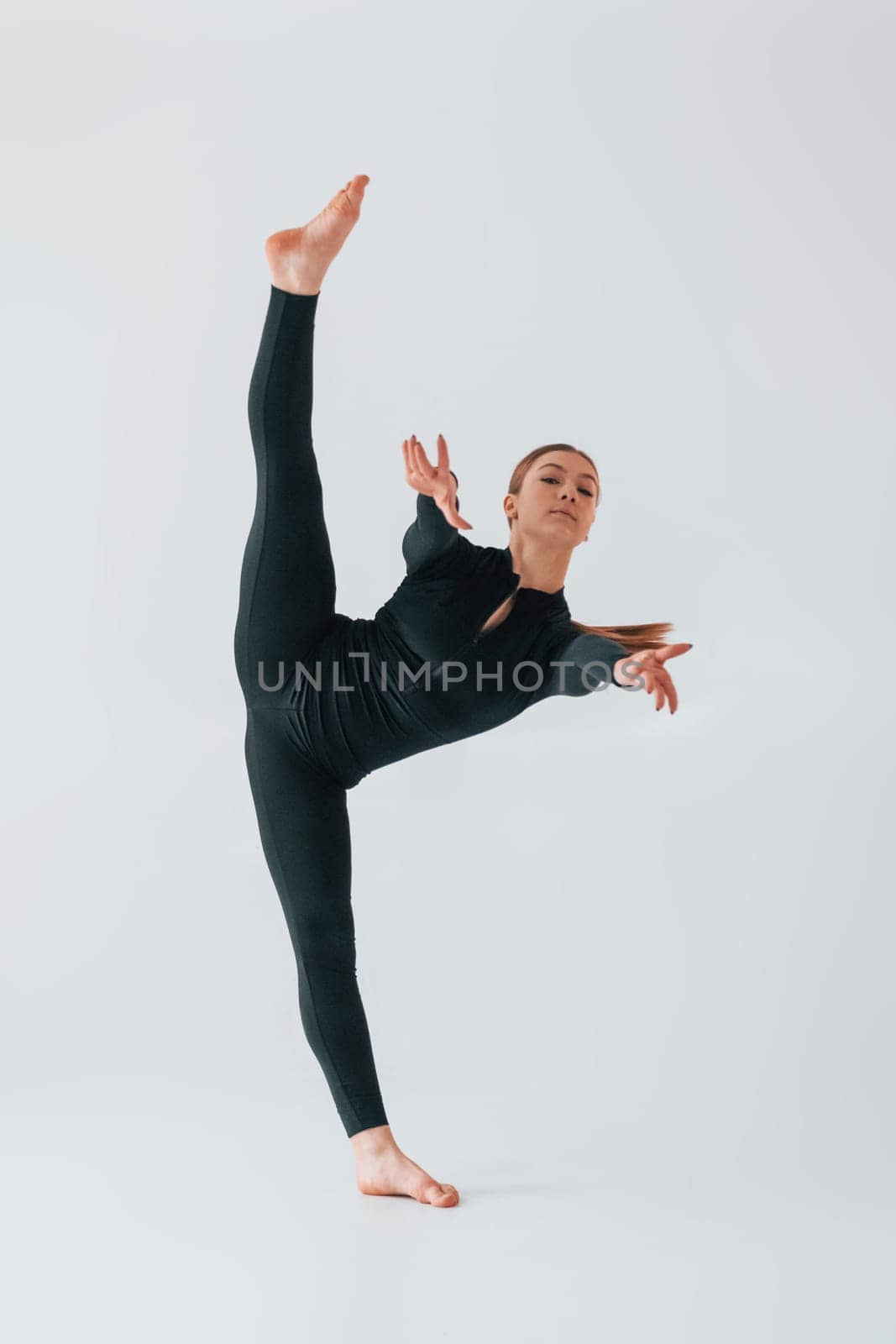 Slim body type. Young woman in sportive clothes doing gymnastics indoors.