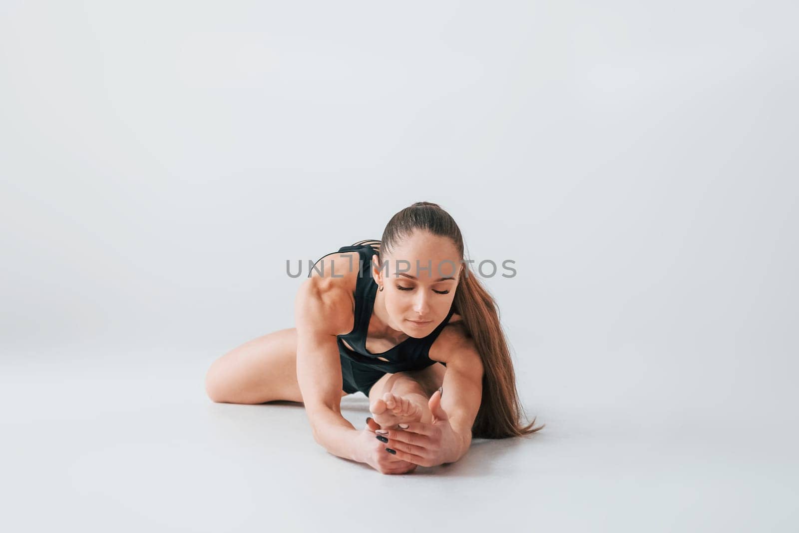 Focused on the exercises. Young woman in sportive clothes doing gymnastics indoors.