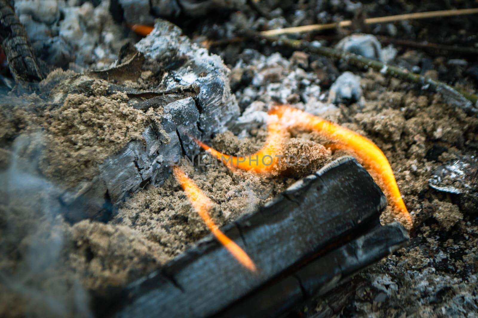 A fire burns in a campfire with a red fire in the background. High quality photo