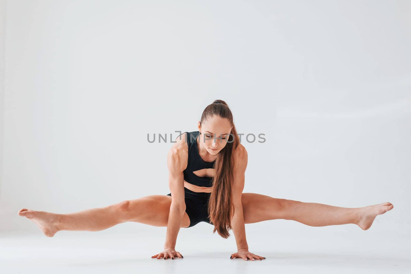 Standing on the hands. Young woman in sportive clothes doing gymnastics indoors.