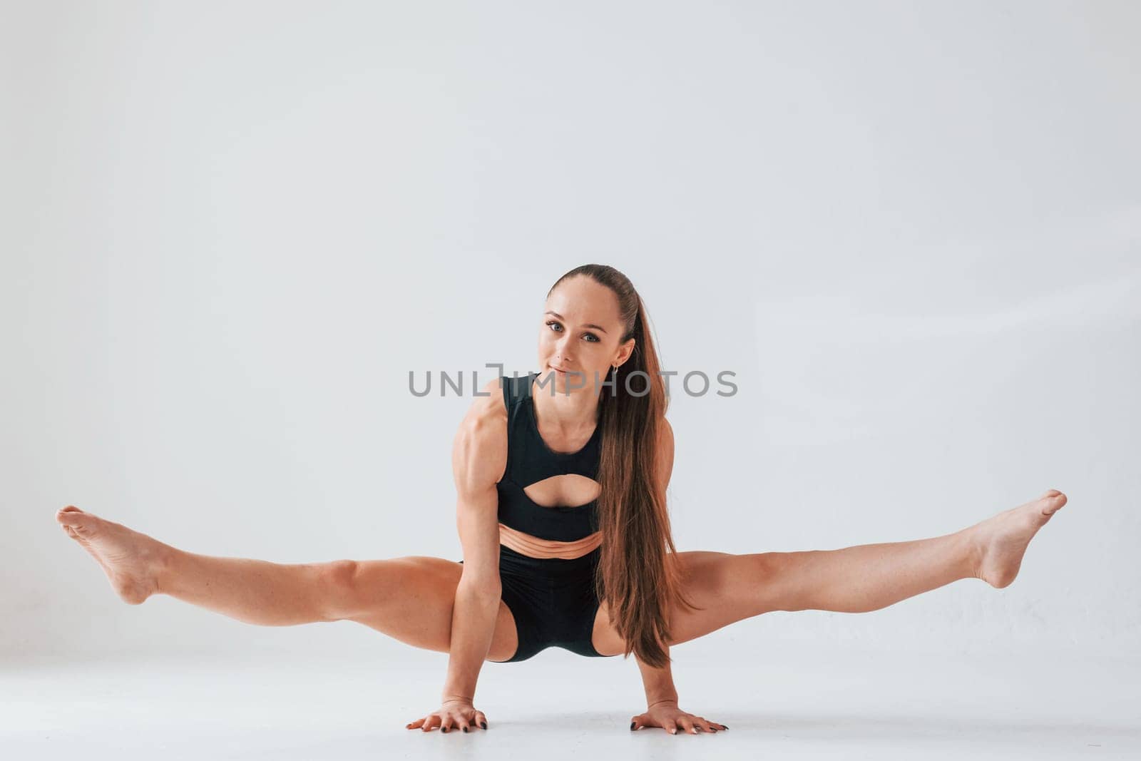 Standing on the hands. Young woman in sportive clothes doing gymnastics indoors.