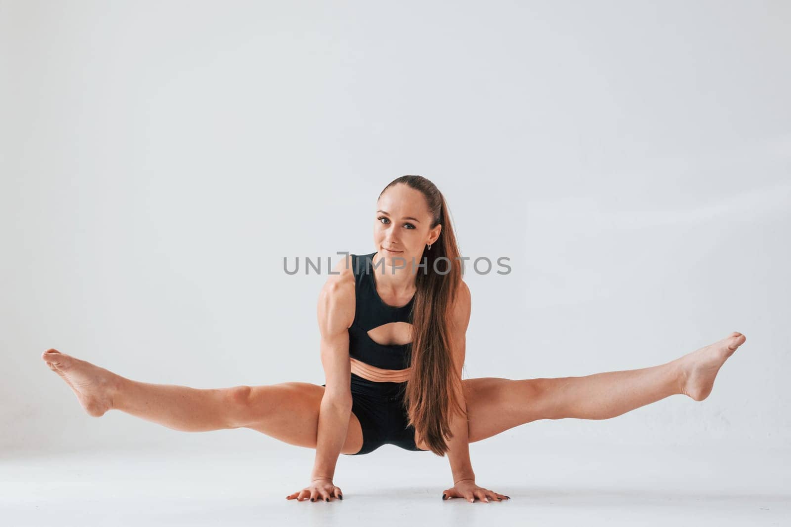 Standing on the hands. Young woman in sportive clothes doing gymnastics indoors.