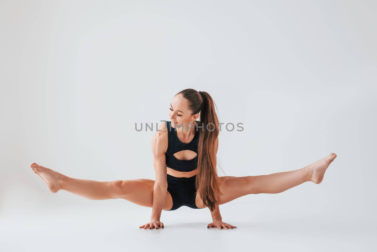 Beautiful body. Young woman in sportive clothes doing gymnastics indoors.