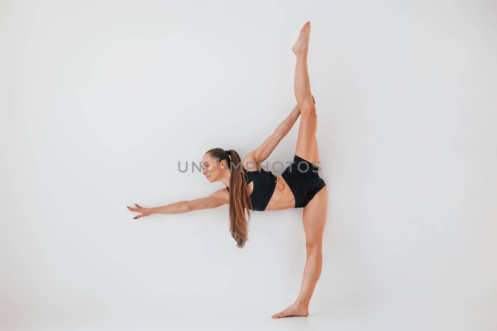 Beautiful body. Young woman in sportive clothes doing gymnastics indoors.