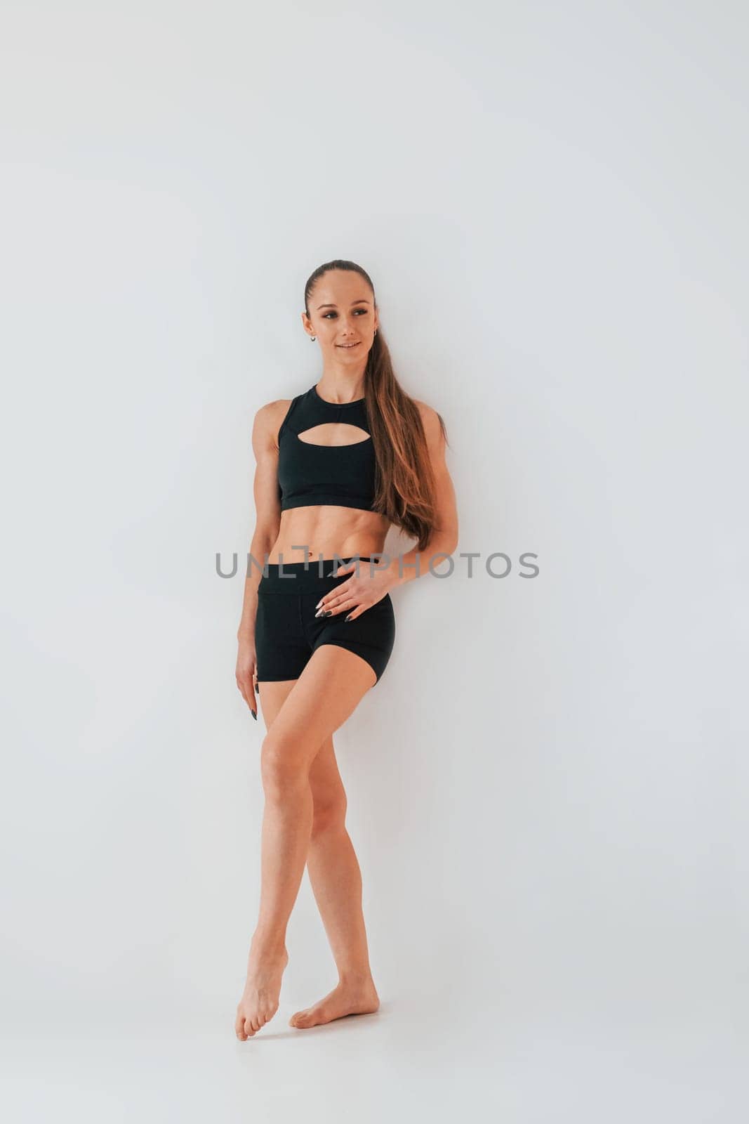 Beautiful body. Young woman in sportive clothes doing gymnastics indoors.