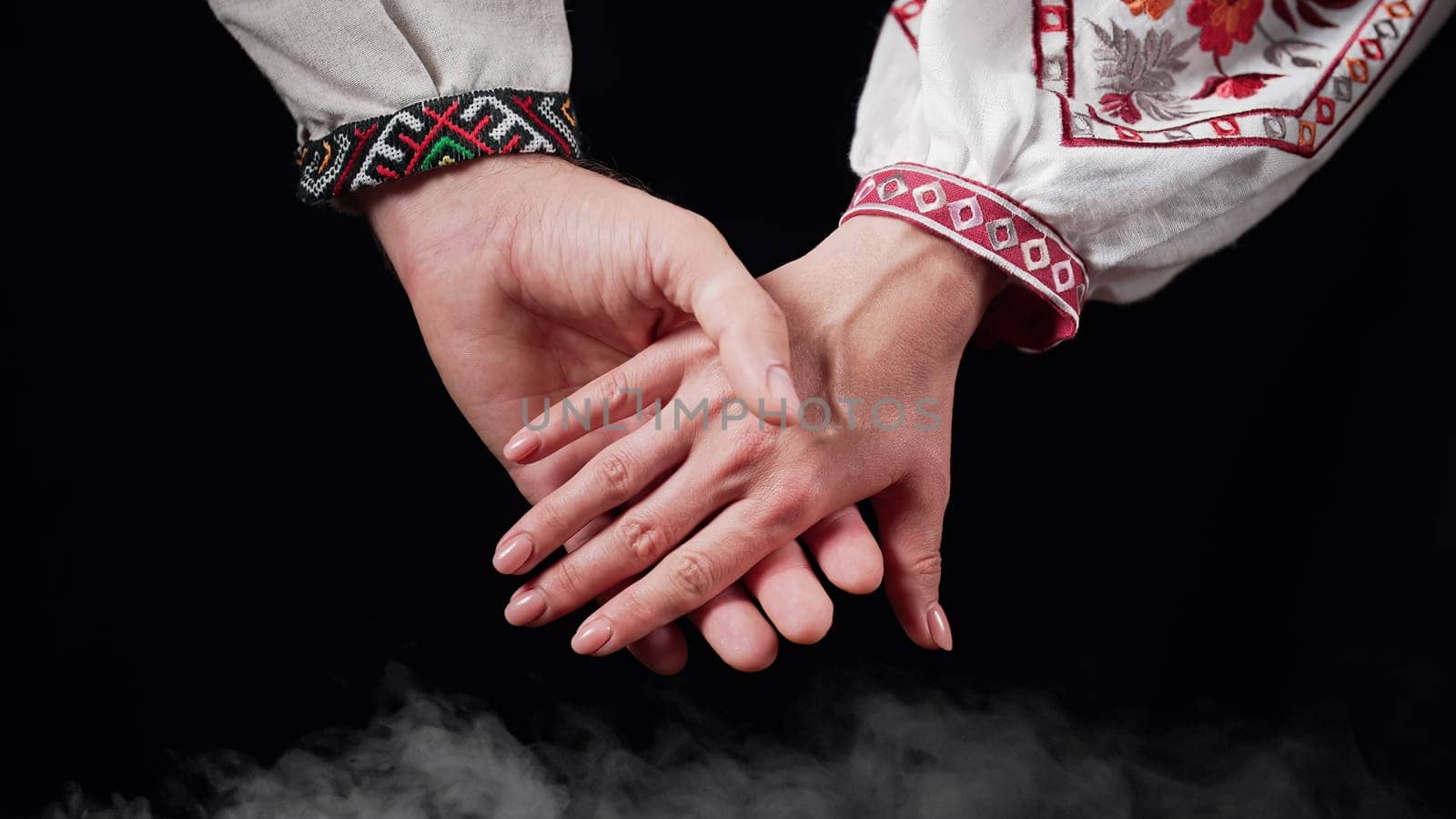 Young ukrainian couple in embroidered national shirts holding hands. Man and woman on black background. Lovers, family, trust, love and happiness concept. High quality