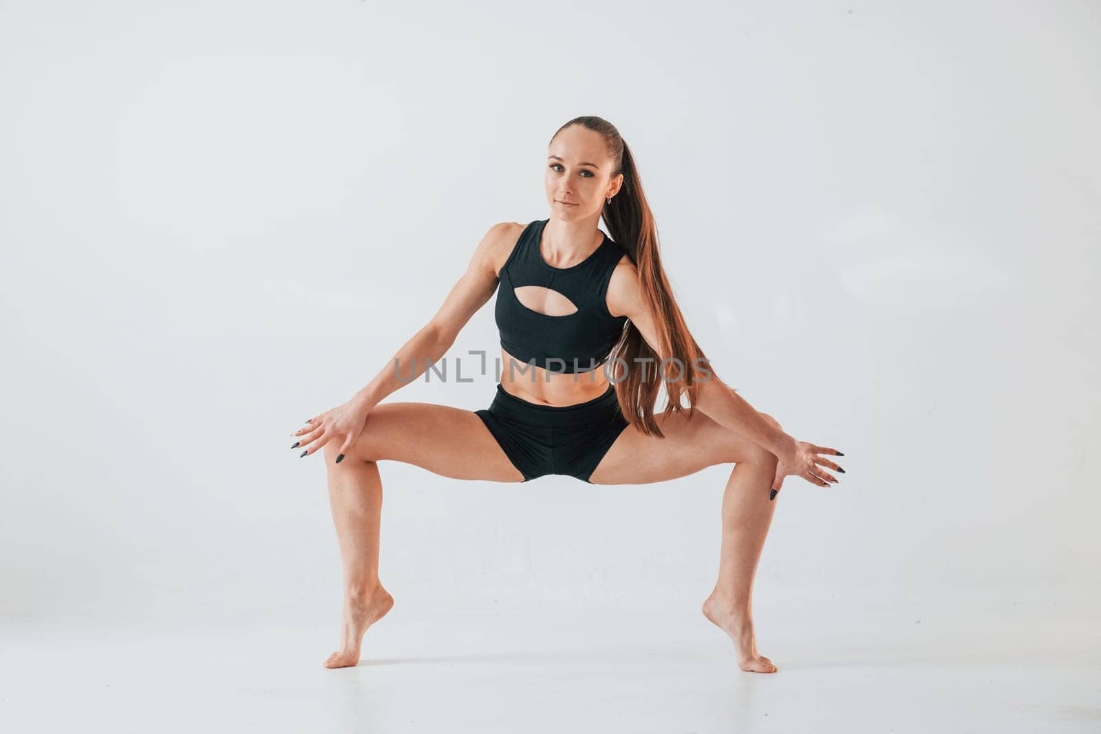 Exercises for stretch and strength. Young woman in sportive clothes doing gymnastics indoors.