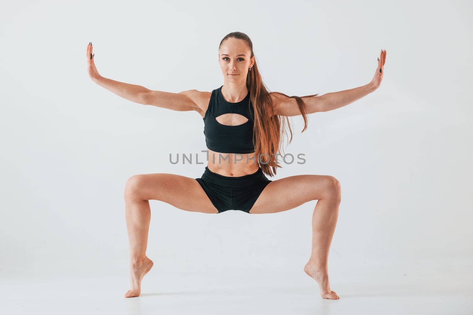 Exercises for stretch and strength. Young woman in sportive clothes doing gymnastics indoors.