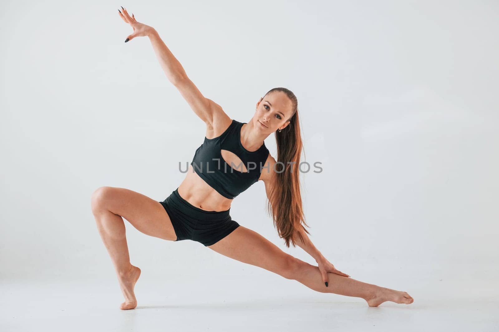 Exercises for stretch and strength. Young woman in sportive clothes doing gymnastics indoors.