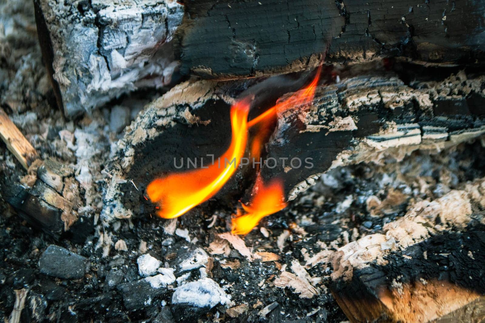 A fire burns in a campfire with a red fire in the background. High quality photo