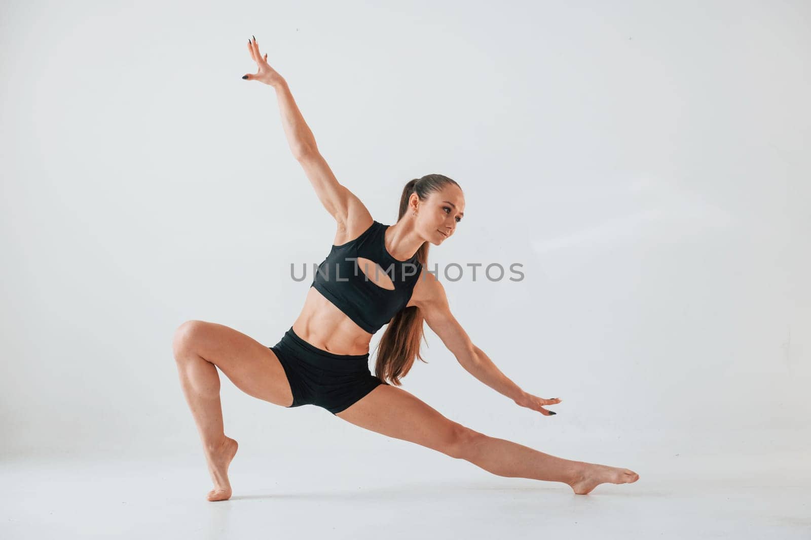 Exercises for stretch and strength. Young woman in sportive clothes doing gymnastics indoors.