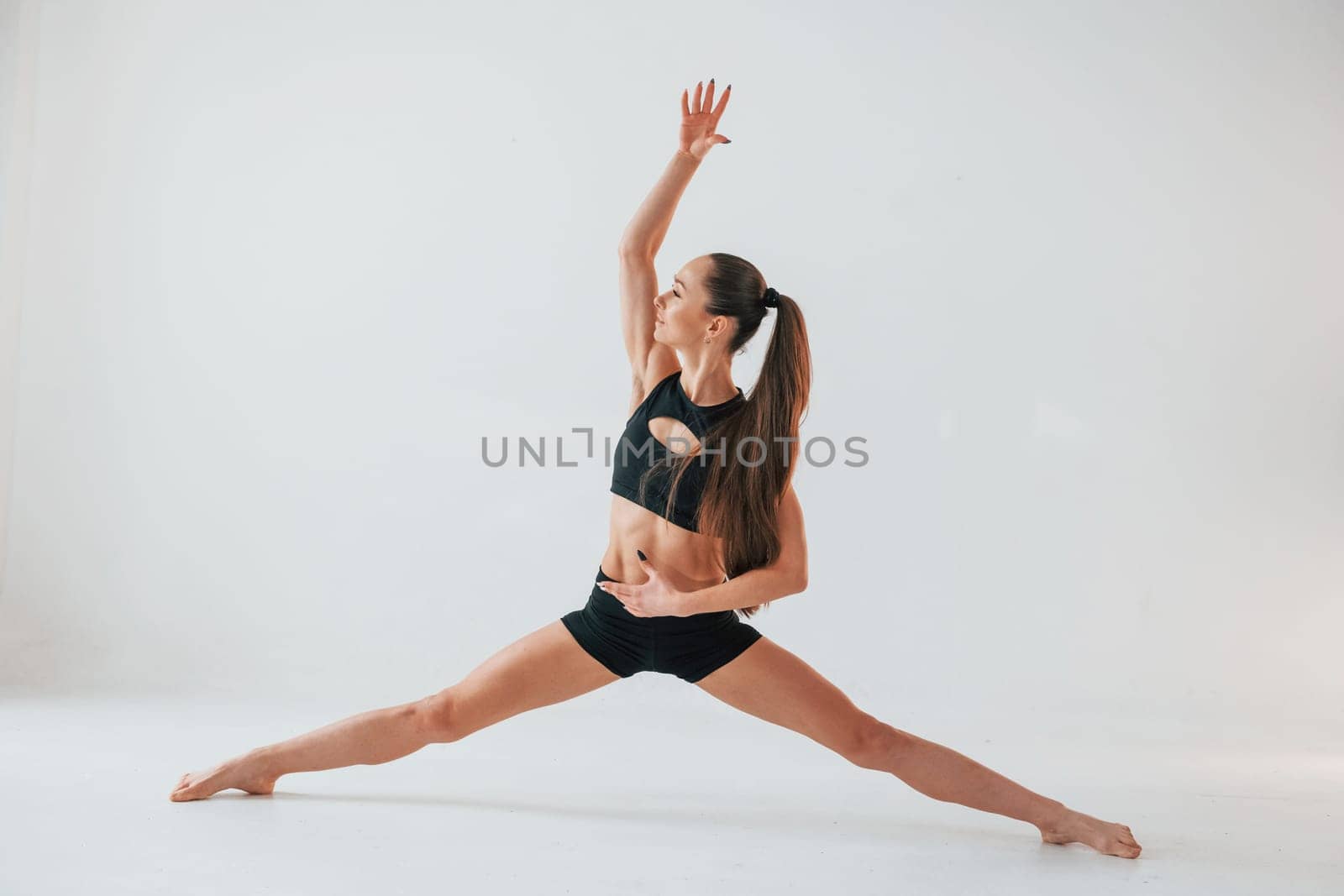 Exercises for stretch and strength. Young woman in sportive clothes doing gymnastics indoors.