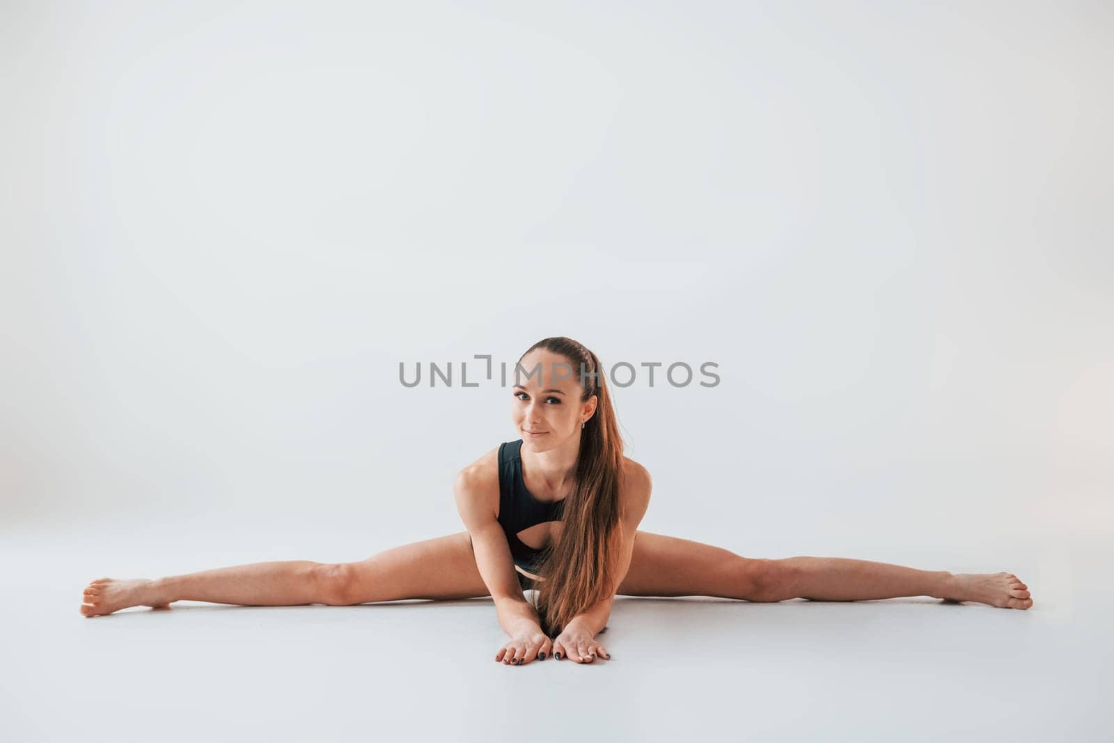 Strong legs. Young woman in sportive clothes doing gymnastics indoors.
