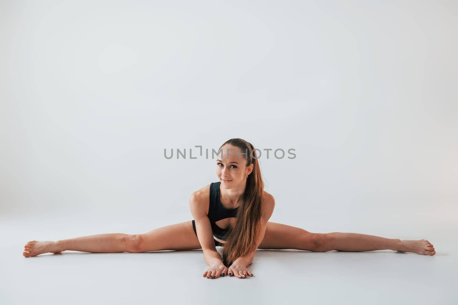 Strong legs. Young woman in sportive clothes doing gymnastics indoors.