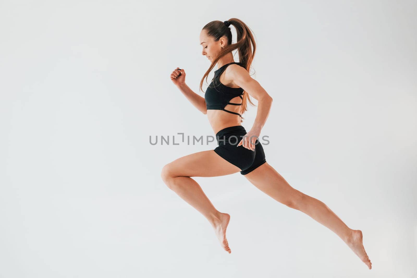 Flexibility of the body. Young woman in sportive clothes doing gymnastics indoors.