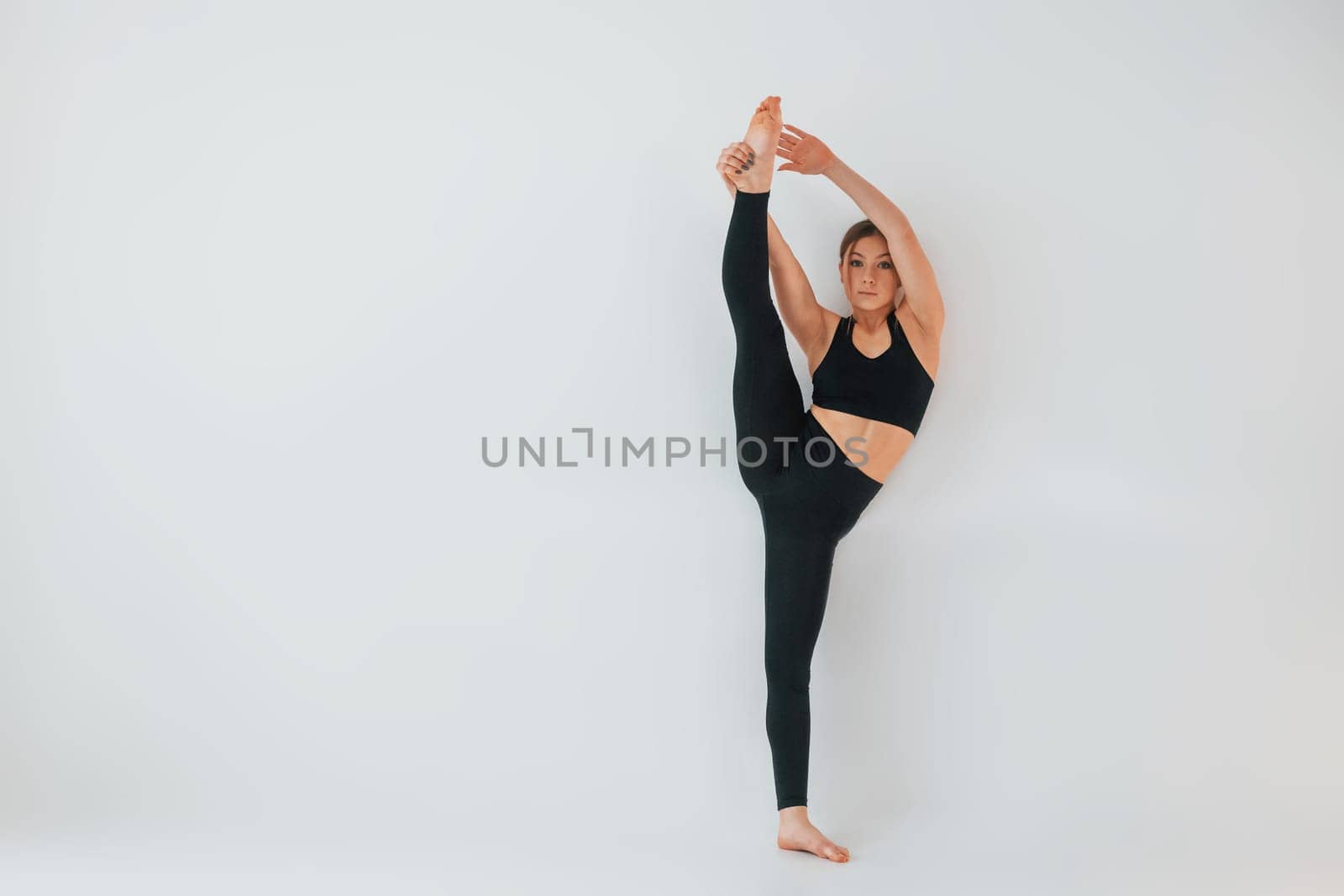 Exercises for the legs. Young woman in sportive clothes doing gymnastics indoors.