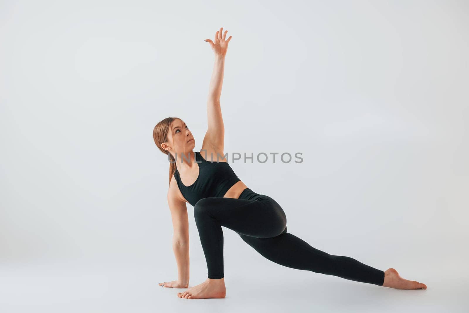 Exercises for the legs. Young woman in sportive clothes doing gymnastics indoors.