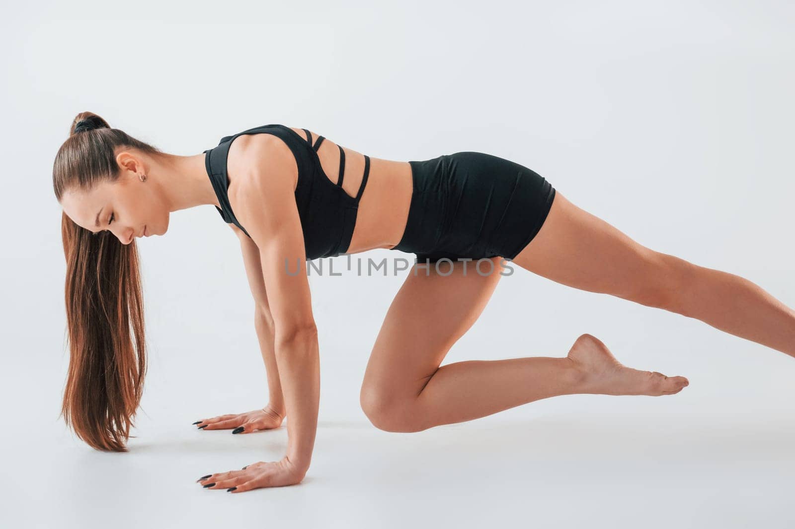 Conception of active lifestyle. Young woman in sportive clothes doing gymnastics indoors.