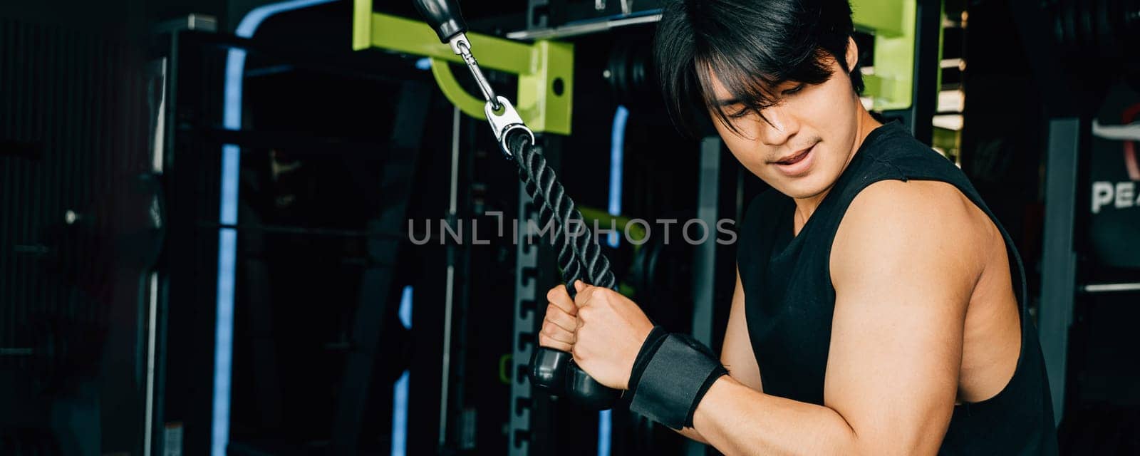 Young man performing cable triceps pulldowns to build muscle and strength by Sorapop
