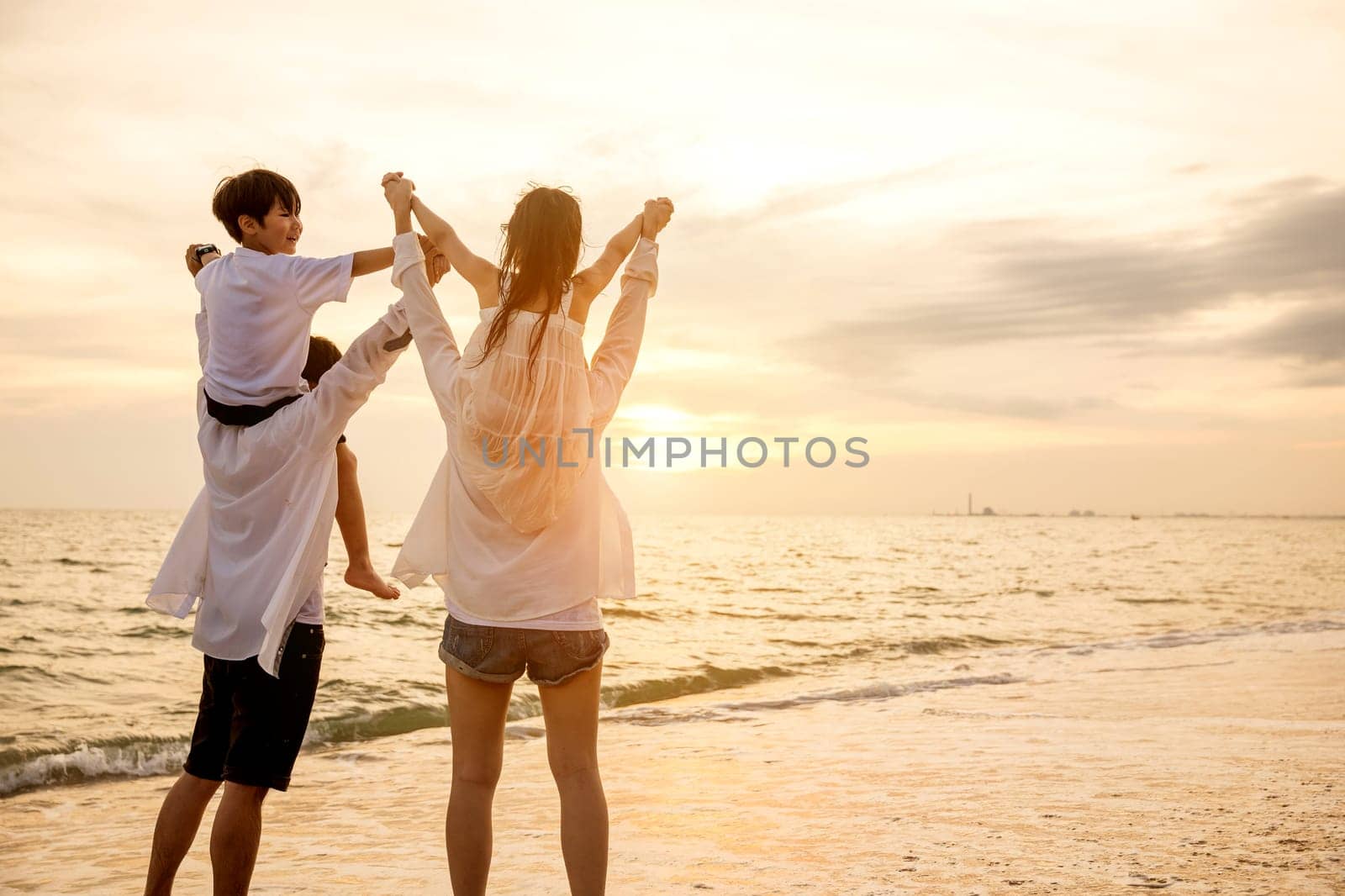 Father carrying son and Mother carrying daughter on shoulder walking summer beach, Parents carrying children on shoulders at beach on sunset, Family on holiday summer vacation, Happy family in holiday