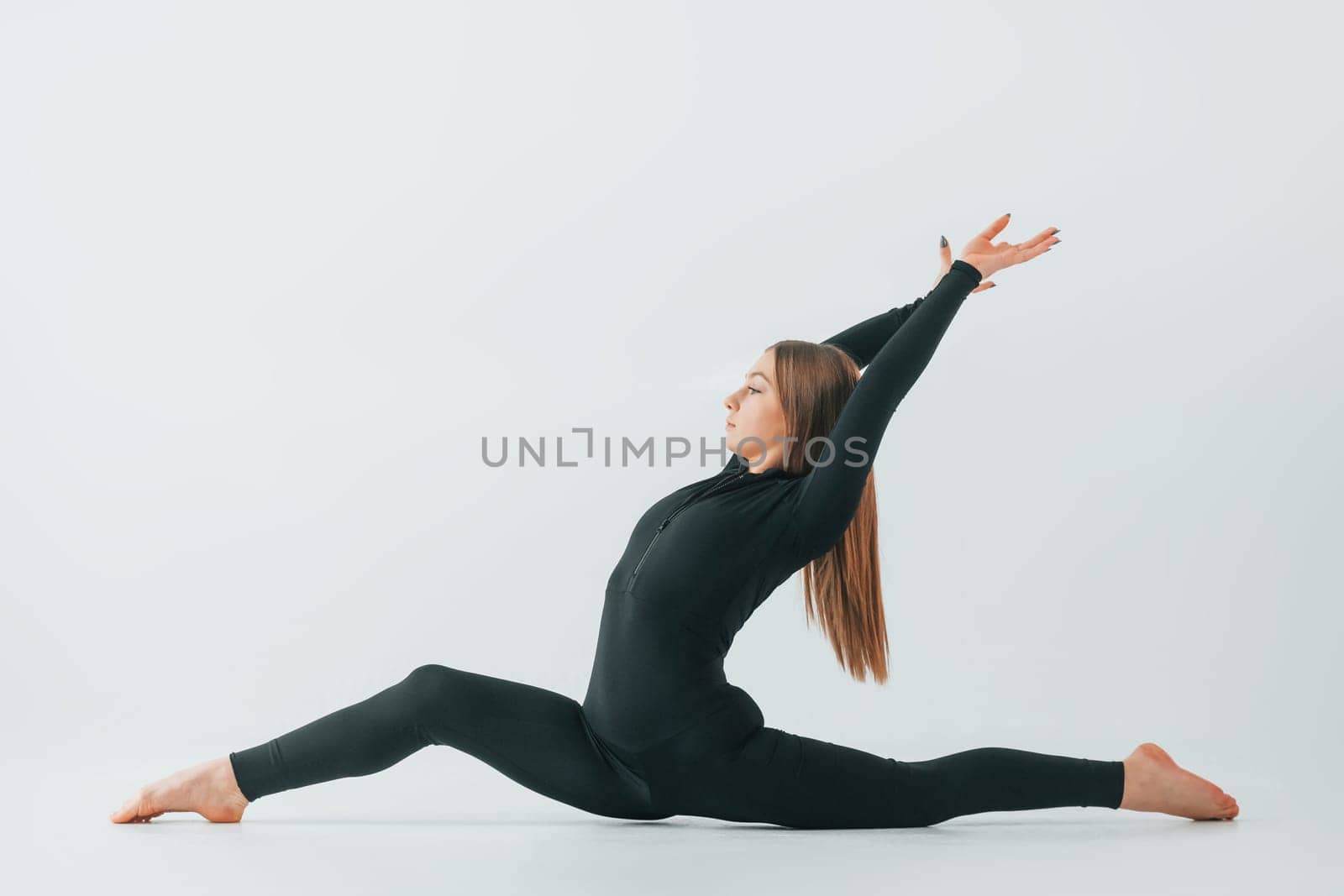 In black sportive clothes. Young woman doing gymnastics indoors.