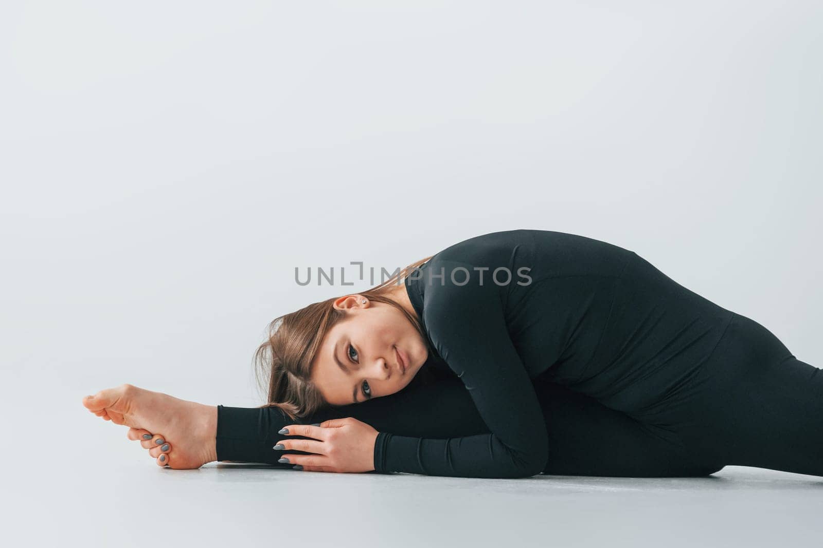 In black sportive clothes. Young woman doing gymnastics indoors.