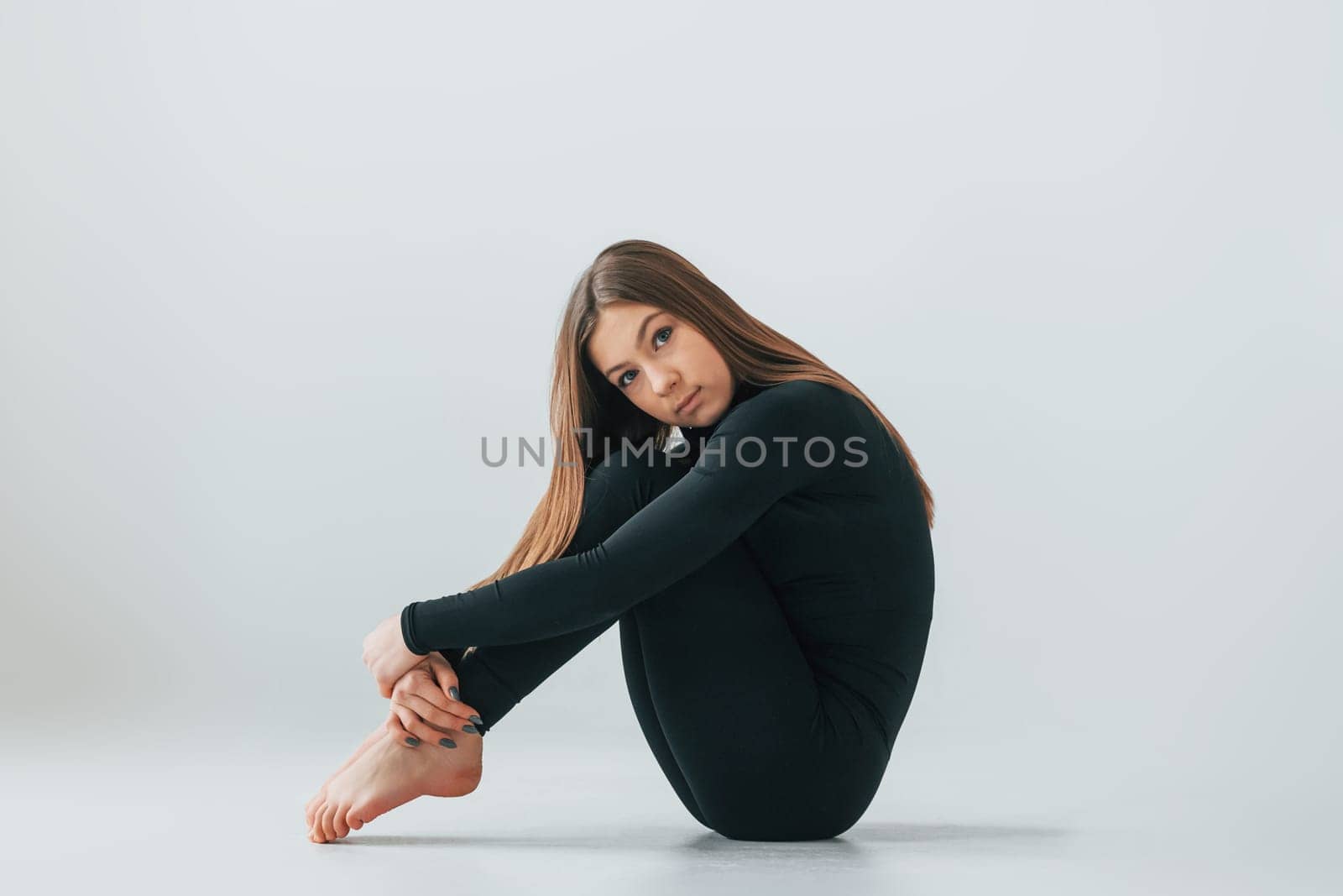 Conception of energy. Young woman in sportive clothes doing gymnastics indoors.