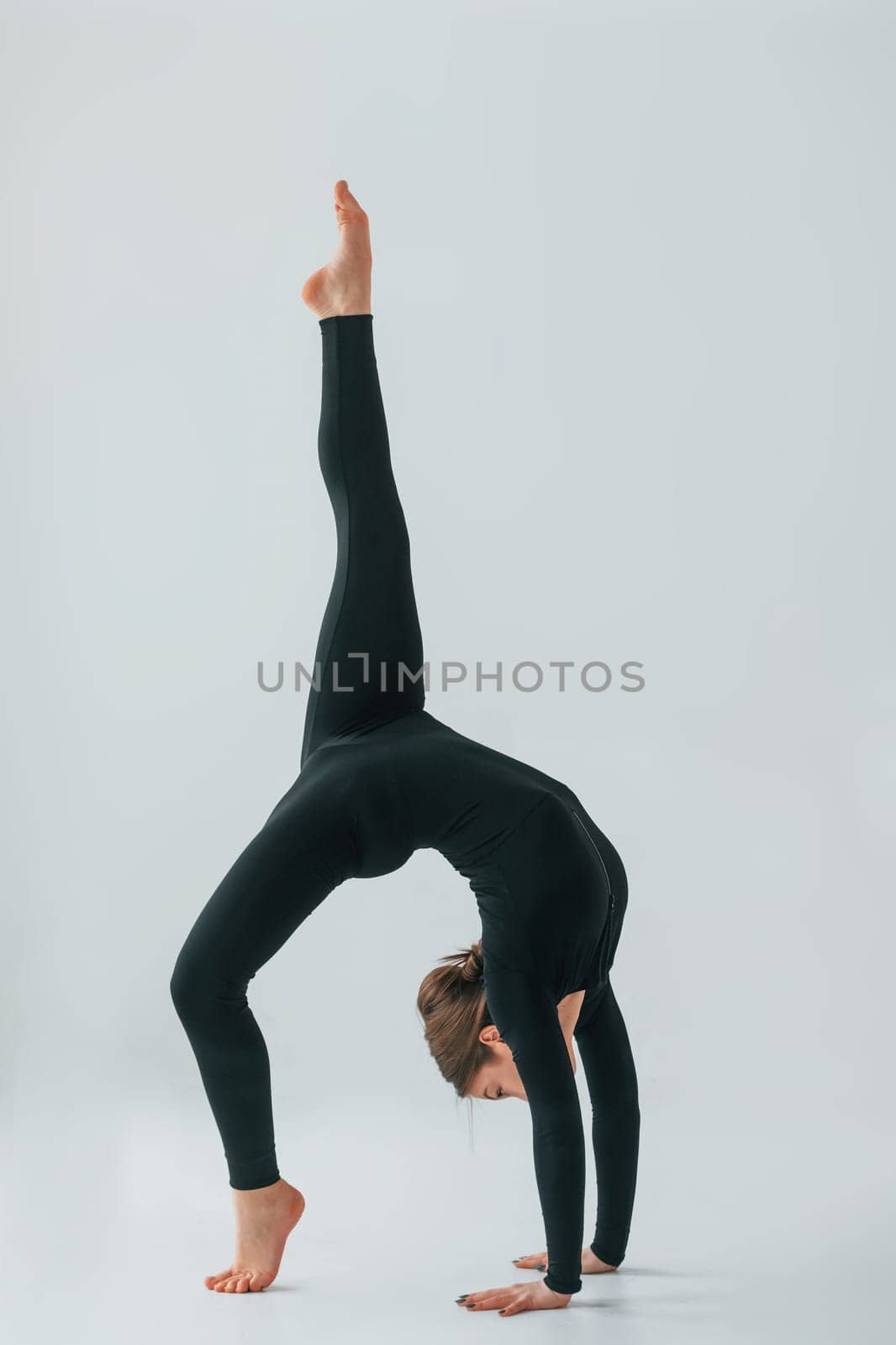 Conception of energy. Young woman in sportive clothes doing gymnastics indoors.
