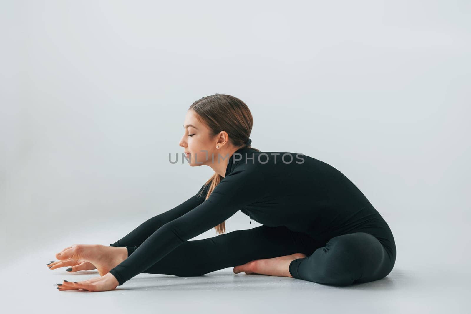 Conception of energy. Young woman in sportive clothes doing gymnastics indoors.
