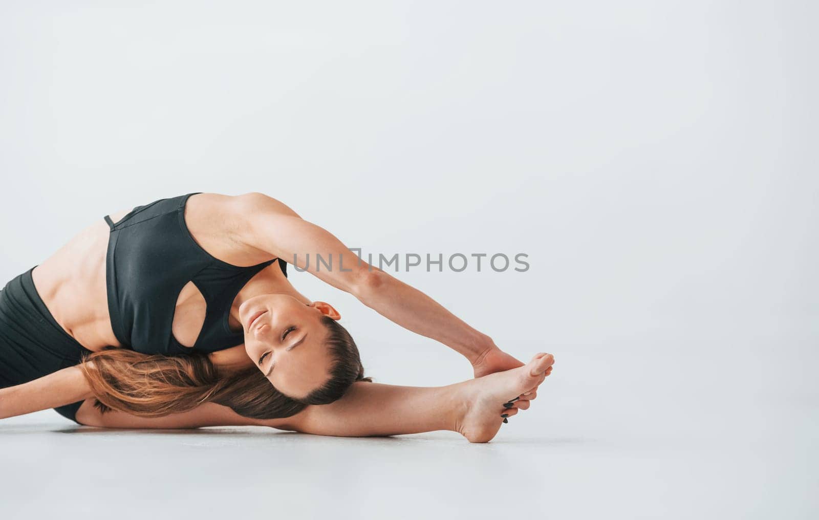 Professional trainer. Young woman in sportive clothes doing gymnastics indoors.
